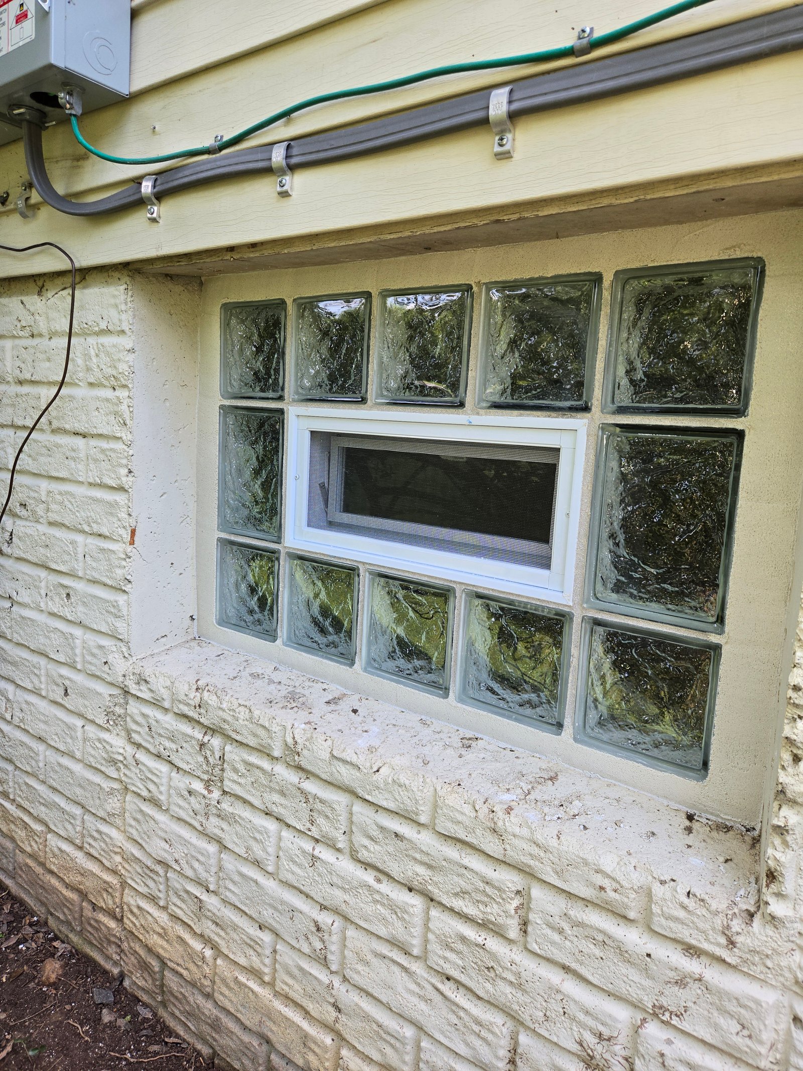 Glass block window with vent in stucco wall